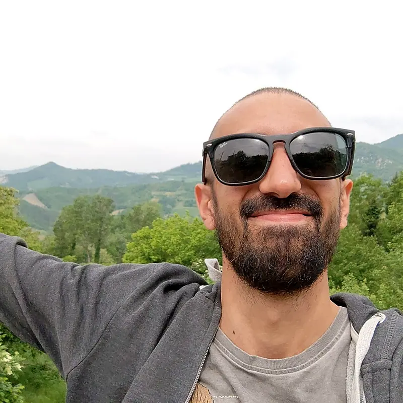 Manuel sorridente con gli occhiali da sole, in collina