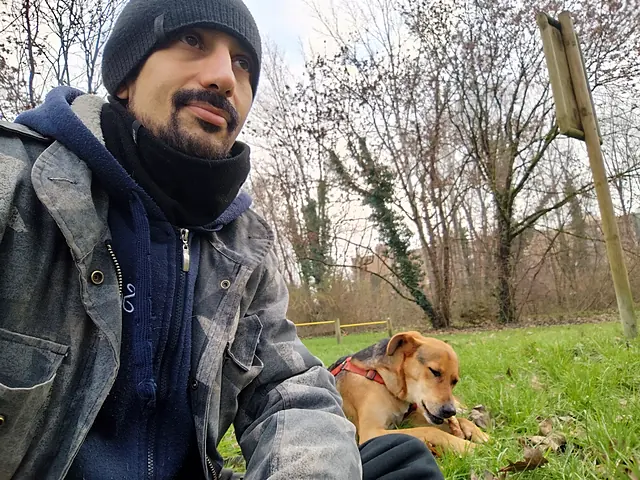 Manuel in un parco, con Dingo sdraiato sul prato accanto a lui